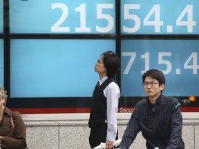 People stand by an electronic stock board of a securities firm in Tokyo, Tuesday, Nov. 13, 2018. Asian stocks sank Tuesday after a tech sell-off dragged Wall Street lower. Tokyo's Nikkei 225 tumbled 3.2 percent to 21,554.45.