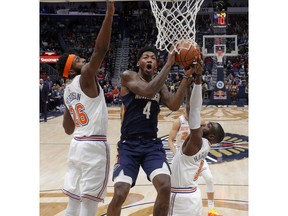 New Orleans Pelicans guard Elfrid Payton (4) goes to the basket between New York Knicks center Mitchell Robinson (26) and guard Tim Hardaway Jr. (3) in the first half of an NBA basketball game in New Orleans, Friday, Nov. 16, 2018.