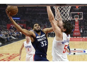 Minnesota Timberwolves center Karl-Anthony Towns, center, shoots as Los Angeles Clippers center Boban Marjanovic, right, of Serbia, defends during the first half of an NBA basketball game Monday, Nov. 5, 2018, in Los Angeles.
