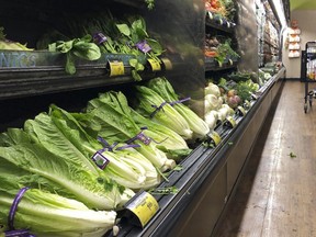 Romaine lettuce still sits on the shelves as a shopper walks through the produce area of an Alberstons market Tuesday, Nov. 20, 2018, in Simi Valley, Calif.