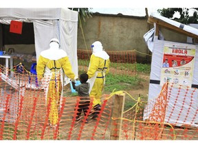 FILE - In this file photo dated Sunday, Sept. 9, 2018, health workers walk with a boy suspected as having the Ebola virus at an Ebola treatment centre in Beni, Eastern Congo.  According to a WHO announcement Thursday Nov. 29, 2018, Congo's deadly Ebola outbreak is now the second largest in history, and predicted the outbreak will last at least another six months before it can be contained.