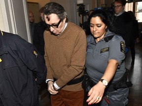 Frenchman Jean-Claude Arnault is escorted from court after the first day of his appeal trial, in Stockholm, Monday, Nov. 12, 2018. Arnault, a major cultural figure in Sweden and the husband of former Swedish Academy member Katarina Frostenson was convicted of rape in October and sentenced to two years in prison.