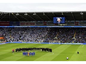 Leicester City players and staff stand with Cardiff City players and match officials during a minute's silence in memory of the victims of the Leicester City helicopter crash which included Chairman Vichai Srivaddhanaprabha during the English Premier League soccer match between Cardiff City and Leicester City at the Cardiff City Stadium, Cardiff. Wales. Saturday Nov. 3, 2018.