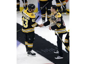 Boston Red Sox pitcher Joe Kelly, right, holds the 2018 World Series championship trophy as he shakes hands with Boston Bruins left wing Brad Marchand (63) prior to a hockey game in Boston, Monday, Nov. 5, 2018.