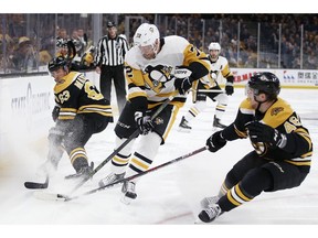 Pittsburgh Penguins' Patric Hornqvist (72) battles Boston Bruins' Brad Marchand (63) and Matt Grzelcyk (48) for the puck during the first period of an NHL hockey game in Boston, Friday, Nov. 23, 2018.