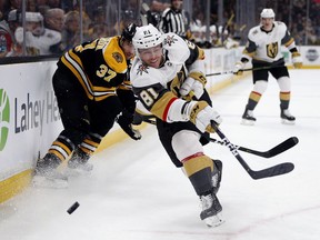 Vegas Golden Knights' Jonathan Marchessault (81) sends the puck along the boards in front of Boston Bruins' Patrice Bergeron (37) during the first period of an NHL hockey game in Boston, Sunday, Nov. 11, 2018.