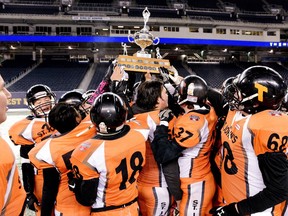 Members of the St. John's Tigers raise the trophy following Winnipeg High School Football League (WHSFL) Division 3 finals action against the Elmwood Giants, in Winnipeg on Thursday, Nov. 8, 2018. The Tigers bested the Giants to end a 38-year championship drought.