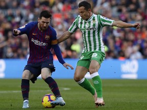 FC Barcelona's Lionel Messi, left, duels for the ball against Betis' Andres Guardado during the Spanish La Liga soccer match between FC Barcelona and Betis at the Camp Nou stadium in Barcelona, Spain, Sunday, Nov. 11, 2018.