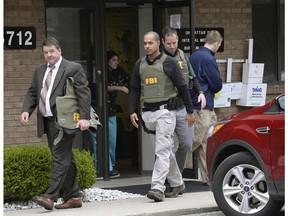 FILE - In this April 21, 2017 file photo, FBI agents leave the office of Dr. Fakhruddin Attar at the Burhani Clinic in Livonia, Mich., after completing a search for documents. A federal judge dismissed some charges Tuesday, Nov. 20, 2018, against eight people, including two doctors, in the genital mutilation of nine girls at the suburban Detroit clinic, finding it's up to states rather than Congress to regulate the practice.