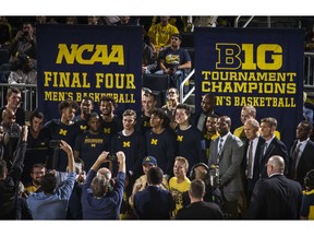 Michigan head coach John Beilein, third from right, poses for photos with his team and newly unveiled Big Ten Tournament Champions and NCAA Final Four banners, before the first half of an NCAA college basketball game against Norfolk State at Crisler Center in Ann Arbor, Mich., Tuesday, Nov. 6, 2018.
