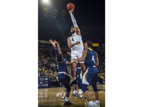 Michigan forward Isaiah Livers (4) attempts to shoot while defended by Chattanooga guards Donovann Toatley, left, and Maurice Commander, right, in the first half of an NCAA college basketball game at Crisler Center in Ann Arbor, Mich., Friday, Nov. 23, 2018.