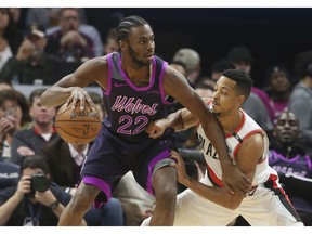 Minnesota Timberwolves' Andrew Wiggins, left, drives against Portland Trail Blazers' CJ McCollum during the first half of an NBA basketball game Friday, Nov. 16, 2018, in Minneapolis. The Timberwolves players paid tribute to the musician Prince, who died in 2016, with new purple-trimmed uniforms.