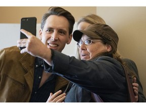 Missouri Attorney General and Republican U.S. Senate candidate Josh Hawley, left, along with his wife Erin Hawley, not shown, pose with another voter for a selfie before voting, Tuesday, Nov. 6, 2018, in Columbia, Mo.