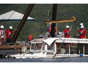 FILE - In this July 23, 2018 file photo, a duck boat that sank during a thunderstorm on July 19, killing 17 people is retrieved on Table Rock Lake in Branson, Mo. Records show a water pump had been replaced with a less powerful system in the tourist duck boat that sank in a Missouri lake. The original Higgins pump, which is capable of removing as much as 250 gallons of water per minute from the bottom of a boat, was replaced with two less powerful electric pumps.