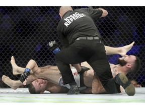 Kurt Holobaugh, left, taps out against Shane Burgos, right, during the first round of a featherweight mixed martial arts bout at UFC 230, Saturday, Nov. 3, 2018, at Madison Square Garden in New York.
