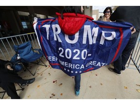 Eva Sara Landau of Diamondhead, Miss., shows off her "Trump 2020" banner cape as she waits admittance to the rally with President Donald Trump, Monday, Nov. 26, 2018, in Biloxi, Miss. Landau and others braved a cold morning to be the first in line to enter the Mississippi Coast Coliseum.