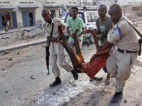 Somalis carry away an injured civilian who was wounded in a bomb blast near the Sahafi hotel in the capital Mogadishu, Somalia, Friday, Nov. 9, 2018. Three car bombs by Islamic extremists exploded outside the hotel, which is located across the street from the police Criminal Investigations Department, killing at least 10 people according to police.