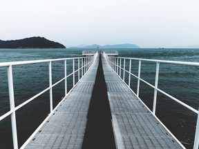 White boat jetty reaching into the dark blue sea of Naoshima, Japan.