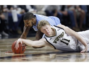 Wofford's Ryan Larson, front, stretches for a loose ball as he battles North Carolina's Seventh Woods, back, during the first half of an NCAA college basketball game in Spartanburg, S.C., Tuesday, Nov. 6, 2018.