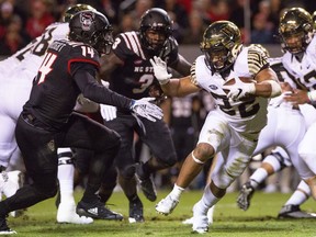 Wake Forest's Matt Colburn II (22) carries the ball as North Carolina State's Dexter Wright (14) looks to make a tackle during the first half of an NCAA college football game in Raleigh, N.C., Thursday, Nov. 8, 2018.