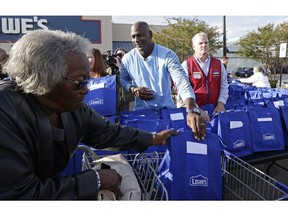 Charlotte Hornets owner Michael Jordan gives a bag of food for Thanksgiving to a woman while greeting members of the community in Wilmington, N.C., Tuesday, Nov. 20, 2018.