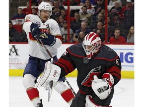 Carolina Hurricanes goaltender Curtis McElhinney (35) blocks a shot as Florida Panthers' Jonathan Huberdeau (11) waits for the rebound during the first period of an NHL hockey game, Friday, Nov. 23, 2018, in Raleigh, N.C.