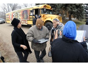 In this Tuesday, Nov. 6, 2018, photo Judith LeBlanc, left, with Four Directions, a non-profit voting equality organization for Native Americans, helps local volunteers Jeff McLaughlin, middle, and Susan Bears Heart before going door-to-door looking for voters in Selfridge, N.D., and offering a free bus ride to the polling precinct. Recent changes to North Dakota's voter identification requirements that some believe were aimed at suppressing the Native American vote didn't cause widespread problems Election Day. Advocacy groups credit an intense effort to ensure a strong Native vote that included free qualifying IDs and free rides to the polls.