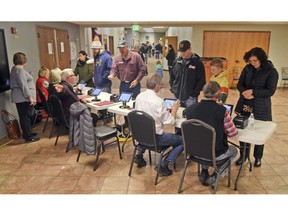 Election workers check identification of each person before receiving a ballot at the northwest Bismarck, N.D., polling place in Century Baptist Church on Tuesday, Nov. 6, 2018.