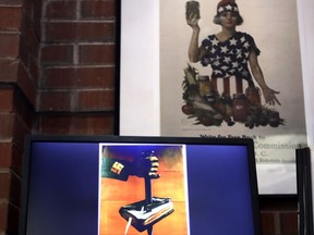 A National War Garden Commission poster copy hangs in a hallway as a display loop shows historic posters on monitor at the Rochester Public Library in Rochester, N.H., Thursday, Nov. 8, 2018. A trove of propaganda posters from World War I and II were found recently found after being lost in storage for decades in the library's basement.