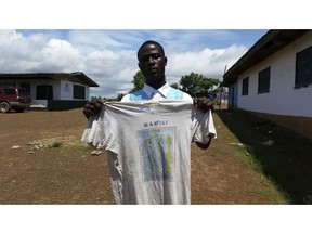 In this photo taken Saturday, Sept. 22, 2018, Moses Z . Kaine, 21 year old , displays a T-Shirt, his father a West Africa peacekeeper, wore to visit his mother, when she was pregnant with him, at a center set up to register and support children left behind by peacekeepers in Liberia, Monrovia. The only memento Moses Z. Kaine has from his father is the T-shirt, left more than two decades ago when the peacekeeper's tour of duty finished and he returned home to leave his pregnant girlfriend behind.