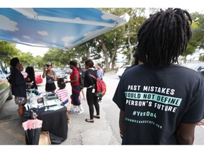 FILE - In this Oct. 22, 2018 file photo, people gather around the Ben & Jerry's "Yes on 4" truck as they learn about Amendment 4 and eat free ice cream at Charles Hadley Park in Miami.  With a single vote Tuesday, Nov. 6, Florida added 1.4 million possible voters to the rolls when it passed Amendment 4, which said that most felons will automatically have their voting rights restored when they complete their sentences and probation.