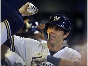 FILE - In this Monday, Sept. 17, 2018 file photo, Milwaukee Brewers' Christian Yelich is congratulated by teammates in the dugout after hitting a two-run home run during the fifth inning of a baseball game against the Cincinnati Reds in Milwaukee. Milwaukee outfielder Christian Yelich was a runaway winner for the National League Most Valuable Player award after helping the Brewers return to the playoffs for the first time in seven years. Yelich received 29 first-place votes and 415 points from the Baseball Writers' Association in balloting announced Thursday, Nov. 15, 2018.