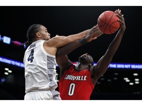 Louisville forward Akoy Agau (0) is fouled by Marquette forward Theo John (4) during the second half of an NCAA college basketball game in the NIT Season Tip-Off tournament Friday, Nov. 23, 2018, in New York. Marquette won 77-74 in overtime.