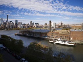 In this Wednesday, Nov. 7, 2018, photo, a rusting ferryboat is docked next to an aging industrial warehouse on Long Island City's Anable Basin in the Queens borough of New York. Across the East River is midtown Manhattan, top left. Long Island City is a longtime industrial and transportation hub that has become a fast-growing neighborhood of riverfront high-rises and redeveloped warehouses, with an enduring industrial foothold and burgeoning arts and tech scenes.