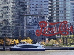 In this Nov. 7, 2018, photo, a water taxi approaches the Long Island City waterfront and new high-rise luxury apartment buildings, passing the landmarked PepsiCola sign in Gantry Plaza State Park in the Queens borough of New York. On Tuesday, Nov. 13, Amazon said it will split its second headquarters between Long Island City in New York and Crystal City in northern Virginia.