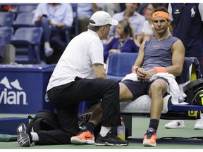 FILE- In this Sept. 7, 2018 file photo, Rafael Nadal, of Spain, is treated by a trainer during a change over against Juan Martin del Potro, of Argentina, during the semifinals of the U.S. Open tennis tournament, in New York. Nadal has pulled out of the season-ending ATP Finals because of an abdominal injury. Nadal announced Monday, Nov. 5 on Twitter that he is done for the year, citing the same stomach muscle issue that forced him to withdraw from last week's Paris Masters. He added that he also would have surgery on his right ankle so he can start 2019 healthy. Nadal hasn't competed since he retired from his U.S. Open semifinal because of a painful right knee.