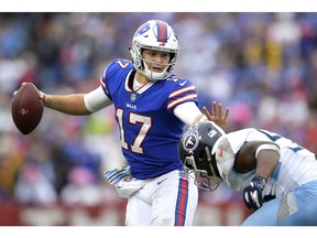 FILE- In this Oct. 7, 2018, file photo, Buffalo Bills quarterback Josh Allen, left, tries to avoid a tackle from Tennessee Titans linebacker Sharif Finch during the second half of an NFL football game in Orchard Park, N.Y. Many teams think it's best to throw rookie QBs right into the fire to learn on the job. Others prefer to gradually work them into the offense. Then, there are some who believe it's more beneficial to have them grab a cap and a clipboard and take it all in from the sideline.