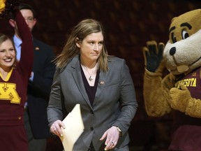 FILE - In this April 13, 2018, file photo, Lindsay Whalen, center, passes by University of Minnesota mascot Goldy Gopher, right, as she is introduced as Minnesota's new women's basketball coach in Minneapolis. The Minnesota women's basketball team has sold out the home opener, a clear sign of the buzz surrounding the program following the hire of the beloved Lindsay Whalen as head coach.