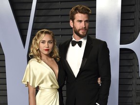 FILE - In this March 4, 2018 file photo, Miley Cyrus, left, and Liam Hemsworth arrive at the Vanity Fair Oscar Party in Beverly Hills, Calif. Though Cyrus and Hemsworth lost their home in the deadly wildfire blazing California, they are donating $500,000 to The Malibu Foundation through Cyrus' charity, The Happy Hippie Foundation.