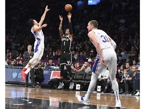 Brooklyn Nets guard D'Angelo Russell (1) shoots a three-point goal past Philadelphia 76ers guard Landry Shamet (23) and forward Mike Muscala (31) during the second half of an NBA basketball game, Sunday, Nov. 4, 2018, in New York.