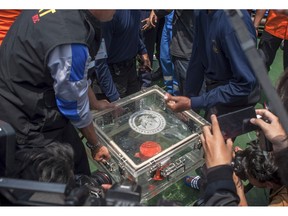 FILE - In this Thursday, Nov. 1, 2018, file photo, members of the National Transportation Safety Committee lift a box containing the flight data recorder from a crashed Lion Air jet onboard a rescue ship anchored in the waters of Tanjung Karawang, Indonesia. Lion Air pilots struggled to maintain control of their Boeing jet as an automatic safety system in the aircraft repeatedly pushed the plane's nose down, according to a draft of a preliminary report by Indonesian officials who are looking into the deadly crash.