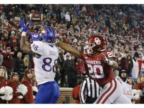 FILE - In this Saturday, Nov. 17, 2018, file photo, Kansas wide receiver Jeremiah Booker (88) makes a catch for a touchdown ahead of Oklahoma safety Robert Barnes (20) during the second half of an NCAA college football game in Norman, Okla. Oklahoma's poor performances on defense have nearly torpedoed one of the best offenses in college football history.