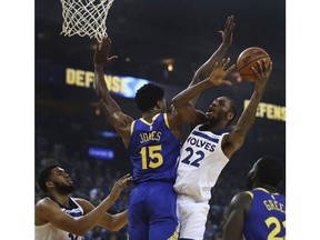 Minnesota Timberwolves' Andrew Wiggins, right, shoots over Golden State Warriors' Damian Jones (15) during the first half of an NBA basketball game Friday, Nov. 2, 2018, in Oakland, Calif.