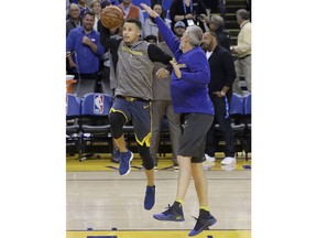 Golden State Warriors guard Stephen Curry, left, warms up with assistant coach Bruce Fraser before the team's NBA basketball game against the Oklahoma City Thunder in Oakland, Calif., Wednesday, Nov. 21, 2018.