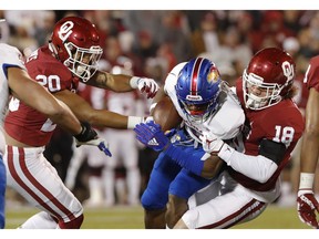 Kansas running back Pooka Williams Jr., center, is tackled by Oklahoma safety Robert Barnes, left, and linebacker Curtis Bolton, right, during the first half of an NCAA college football game in Norman, Okla., Saturday, Nov. 17, 2018.