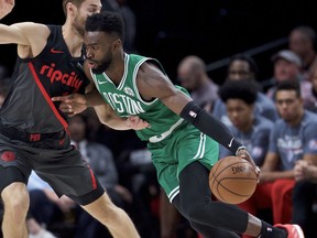 Boston Celtics guard Jaylen Brown, right, dribbles past Portland Trail Blazers forward Jake Layman during the first half of an NBA basketball game in Portland, Ore., Sunday, Nov. 11, 2018.