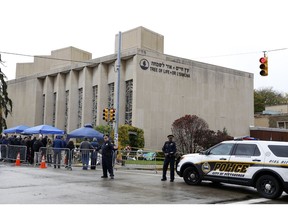 Pittsburgh Police direct traffic as their vehicles close the street adjacent to the Tree of Life Synagogue on Saturday, Nov. 3, 2018, as a curbside Shabbat morning service is held on the street corner in the Squirrel Hill neighborhood of Pittsburgh. The service honored the 11 people killed by a gunman, Oct 27, 2018 while worshipping at the Tree of Life Synagogue.