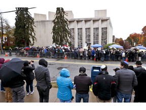 People line both sides of the street as they gather outside the Tree of Life Synagogue for a service on Saturday, Nov. 3, 2018, in Pittsburgh.  About 100 people gathered in a cold drizzle for what was called a "healing service" outside the synagogue that was the scene of a mass shooting a week ago.