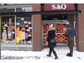 A couple walks up to a closed liquor store in Montreal on Friday, November 16, 2018. Unionized employees with the Quebec Liquor Corp. walked off the job today and will remain on strike until Monday.