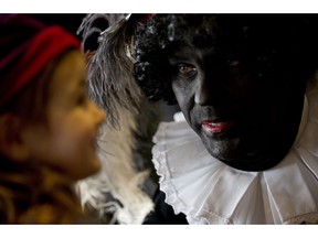 In this Friday Dec. 5, 2014 file photo three-and-a-half-year-old Ita Krans, left, talks to Black Pete, the black-faced sidekick of Sinterklaas, the Dutch version of Santa Claus, during a short ceremony at the mayor's office in Amsterdam, Netherlands. As many Dutch children eagerly anticipate the arrival of their country's version of Santa Claus this weekend, opponents and supporters of his controversial helper Black Pete are gearing up for protests. Black Pete is often played by white people with their faces daubed in dark makeup. Supporters see him as a traditional children's character, while opponents decry him as a racist stereotype.